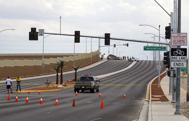 A pedestrian, left, talks with a Metro Police officer as officials investigate an accident between a car and a Metro Police motorcycle officer on the Durango Drive Drive overpass over the Summerlin Parkway Wednesday, May 8, 2013.