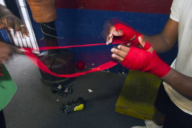 Mike McCallum Sr. helps remove hand wrap from his son's hands during a workout at Johnny Tocco's Boxing Gym Thursday, May 9, 2013.  Mike McCallum Sr., known as the "Body Snatcher" for his fierce body punching, won world titles in three weight divisions.