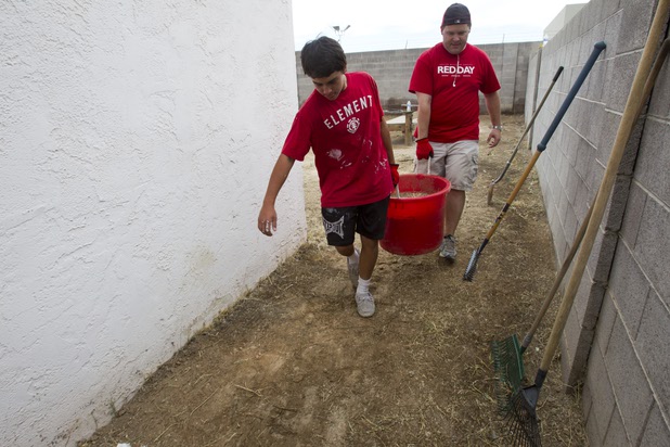Adam Wahl, 14, a Foothills High School student, and Keller Williams realtor Shawn Marion carry yard waste as they clean up the backyard of a home near Boulder Highway and Sahara Avenue Thursday, May 9, 2013. The associates were among more than 70,000 workers around the world participating in the fifth annual Keller Williams RED Day. RED Day (Renew, Energize and Donate) is an initiative where Keller Williams associates donate a day to give back to the community.