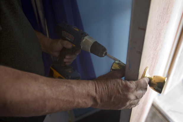 Larry Bishop, a Keller Williams field agent, installs a lock as associates from the Market Place Offices work on a home near Boulder Highway and Sahara Avenue Thursday, May 9, 2013. Every lock on the house had a different key so Bishop rekeyed the locks to work with one key. The associates were among more than 70,000 workers around the world participating in the fifth annual Keller Williams (Renew, Energize and Donate) RED Day.