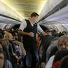 In this Thursday, May 9, 2013, photo, Allegiant Air flight attendant Chris Killian prepares his passengers for the Laredo, Texas-bound flight before it pushes back from the terminal at McCarran International Airport in Las Vegas. 