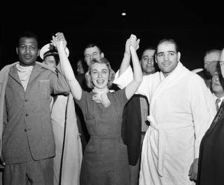 Dr. Joyce Brothers, 28-year-old psychologist who won $64,000 television quiz on boxing knowledge, holds up arms of challenger Sugar Ray Robinson, left, and middleweight champ Carl 
