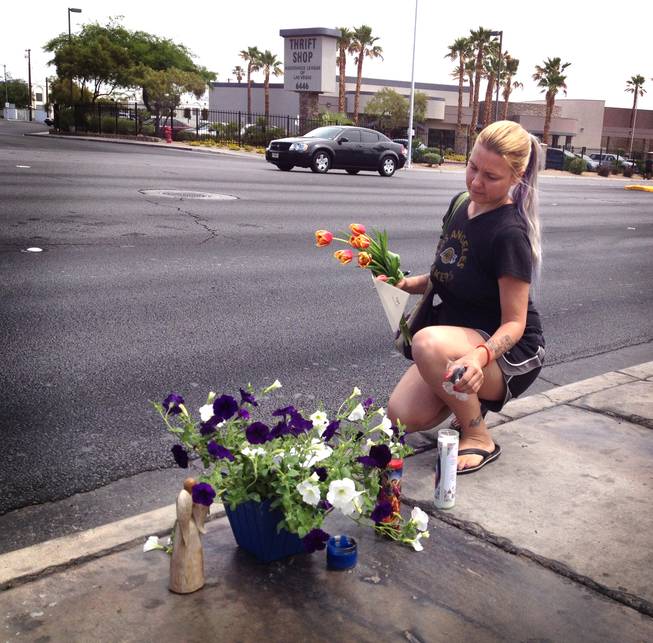 Renee Gardner, 38, adds a bouquet of flowers, card and candle to a memorial for 15-year-old Marcos Vincente Arenas on Friday, May 17, 2013. Metro Police say Arenas, a freshman at Bonanza High School, was run over the previous day as he was being robbed of his iPad. Arenas was transported to University Medical Center, where he died of his injuries.

