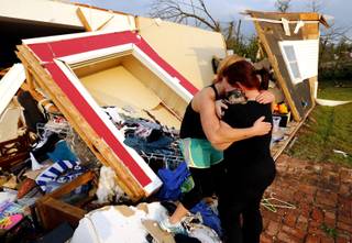 Alli Christian, left, returns Jessica Wilkinson's dog Bella to her after finding her among the wreckage of Wilkinson's home shortly after a tornado struck near 156th street and Franklin Road on Sunday, May 19, 2013  in Norman, Okla. No one was in the home when the storm struck. 