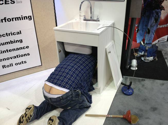A "plumber" fixes a sink at Ideal Services' booth at RECon, the retail industry trade show at the Las Vegas Convention Center, on May 20, 2013. The mannequin was used to demonstrate one of many problems that could result from hiring the wrong repairman.