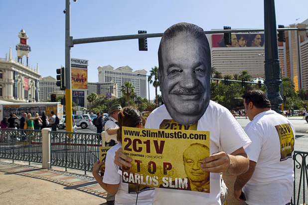 Justin McAffee, center, wears a Carlos Slim mask as members of Two Countries One Voice protest against Carlos Slim, a Mexican businessman listed as the second richest man in the world by Bloomberg's Billionaire Index, in front of the Venetian Wednesday, May 22, 2013. The group accuses Slim's telecommunication companies of engaging in predatory and monopolistic practices. The protest coincides with CTIA, a wireless technology convention, being held at the Sands Expo Center.
