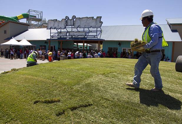 A landscaper works on a grassy area as people wait to pick up passes at the Wet 'n' Wild Las Vegas water park, 7055 S. Fort Apache Road, Wednesday, May 22, 2013. The new 41-acre park opens to Gold Pass holders on Saturday. Single day tickets are available from June 3.
