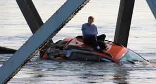 In this photo provided by Francisco Rodriguez, a man is seen sitting atop a car that fell into the Skagit River after the collapse of the Interstate 5 bridge there minutes earlier Thursday, May 23, 2013, in Mount Vernon, Wash. 