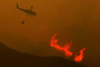 A helicopter prepares to drop a load of water on the Power House fire that has burned hundreds of acres in Green Valley, Calif.  on Thursday, May 30, 2013.  The wildfire in the mountains north of Los Angeles has been slowed by morning overcast but authorities say about 25 homes have been evacuated as scattered flames continue to leap hillsides. Authorities Friday morning ordered homes evacuated on San Francisquito Canyon Road in the Angeles National Forest north of Castaic. 