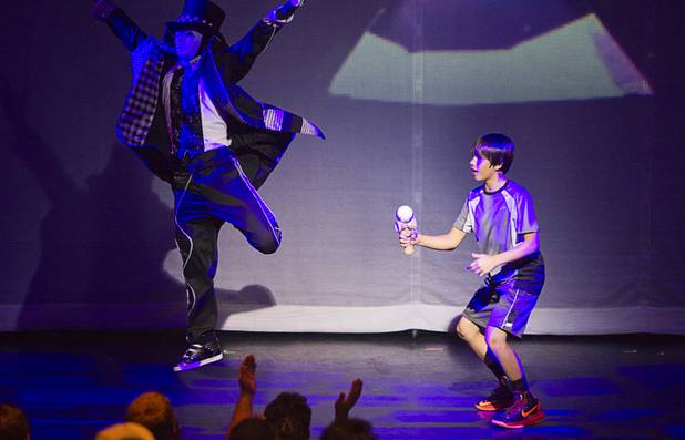 A Jabbawockeez cast member jumps as audience member Eric Ho successfully lands a ball on a stick before a performance of "Prism," the new Jabbawockeez show at the Luxor, Sunday, June 9, 2013.