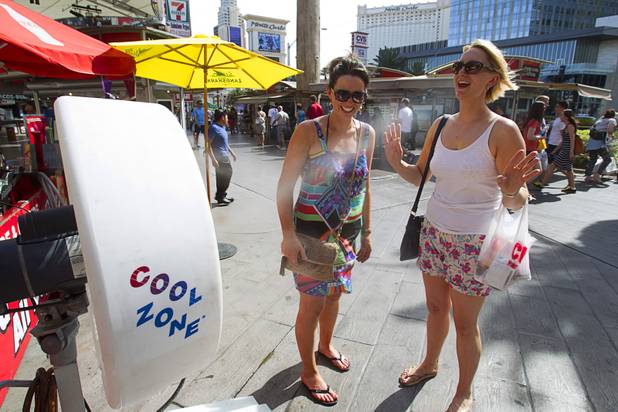 Marie Kennedy, left and Karen Curtin, both of Ireland, cool down in front of a misting fan on the Las Vegas Strip Sunday, June 9, 2013. 