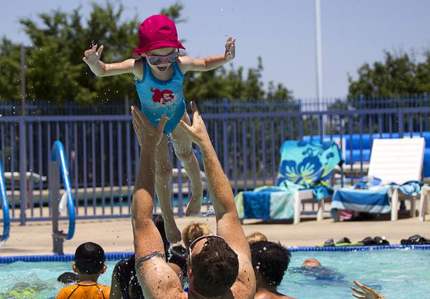 Jasmine Atkins, 3, is tossed in the air by her father Moshe Atkins at the Henderson Multigenerational Activity Pool Sunday, June 9, 2013. 