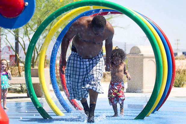 Jovon Kelly and his son Justice William Kelly, 4, run through a water feature at Charlie Frias Park Sunday, June 9, 2013. Sunday's high temperature was 109, two degrees shy of the record.
