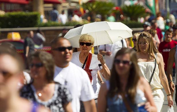 A woman uses an umbrella for shade as she walks along the Las Vegas Strip Sunday, June 9, 2013.