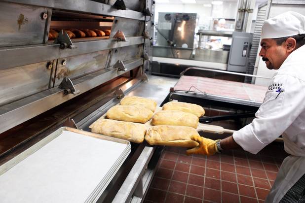 Baker Carlos Meza pulls fresh bread out of the oven inside the basement bakery at Caesars Palace in Las Vegas on Tuesday, June 11, 2013.
