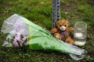 A teddy bear, flowers and a candle are the only items left at the entrance to Sandy Hook Elementary School on the six-month anniversary of the Dec. 14 shooting in Newtown, Conn., Friday, June 14, 2013. Newtown held a moment of silence Friday for the victims of the massacre at Sandy Hook Elementary School at a remembrance event that doubled as a call to action on gun control, with the reading of names of thousands of victims of gun violence.
