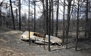 A burned automobile sits off the roadside in the burned forest on the Black Forest wildfire north of Colorado Springs, Colo., on Monday, June 17, 2013. Over 470 homes burned in the wildfire that started last Tuesday. 