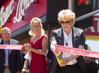 Las Vegas Mayor Carolyn Goodman, right, uses a torch to cut a tape during the grand reopening of The Atomic on East Fremont Street Wednesday, June 20, 2013. Looking on are Allan Palmer, left, CEO/executive director of the National Atomic Testing Museum, and Jennifer Albright. The bar was was originally built in 1945 as Virginia's Cafe but was renamed Atomic Liquors in 1952 when patrons used to go to the roof to watch the nuclear blasts from the Atomic Test Site.