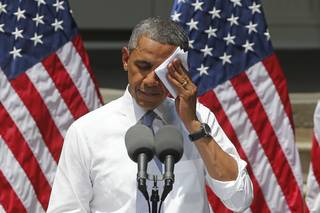 President Barack Obama wipes his face as he speaks about climate change, Tuesday, June 25, 2013, at Georgetown University in Washington. The president is proposing sweeping steps to limit heat-trapping pollution from coal-fired power plants and to boost renewable energy production on federal property, resorting to his executive powers to tackle climate change and sidestepping the partisan gridlock in Congress.