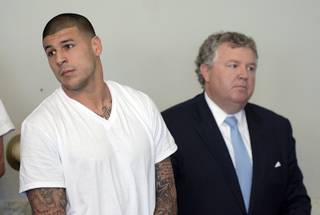 Former New England Patriots tight end Aaron Hernandez, left, stands with his attorney Michael Fee, right, during arraignment in Attleboro District Court Wednesday, June 26, 2013, in Attleboro, Mass.