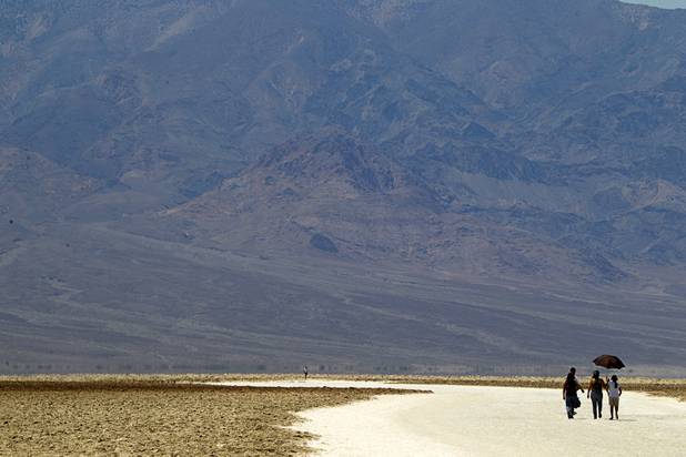 A group of tourists use an umbrella for shade at Badwater Basin, 282 feet (85.5m) below sea level, in Death Valley National Park Saturday, June 29, 2013.