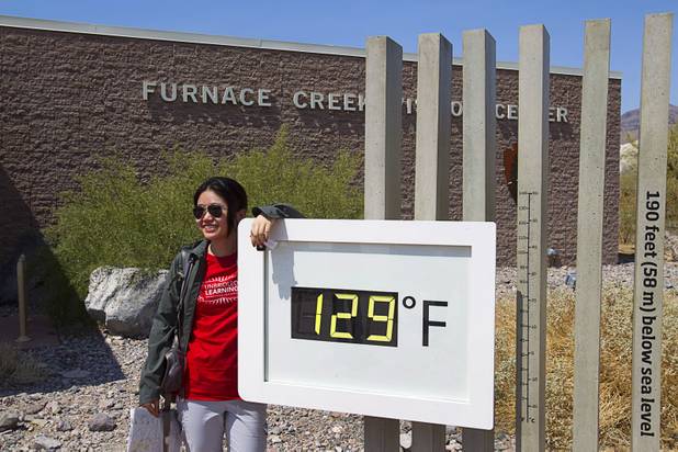 Jing Jing, a student from China, poses in front of an unofficial temperature gauge at the Furnace Creek Visitor Center in Death Valley National Park Saturday, June 29, 2013.