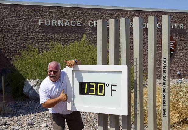 Craig Blanchard, a Park Service employee, poses in front of an unofficial temperature gauge at the Furnace Creek Visitor Center in Death Valley National Park Saturday, June 29, 2013.