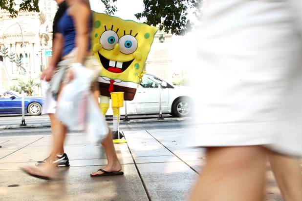A man wearing a SpongeBob outfit waits in the shade to have his photo taken for tips on the Strip Saturday, June 29, 2013.