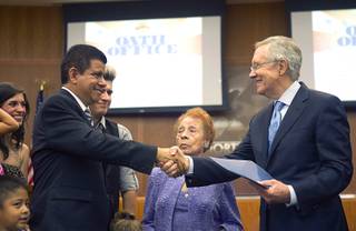 Councilman Isaac Barron, left, shakes hands with Senate Majority Leader Harry Reid (D-NV) during an oath of office ceremony at North Las Vegas City Hall Monday, July 1, 2013. Barron is the first Hispanic to serve on the North Las vegas city council.  Barron's aunt Socorro Molina looks on at center.