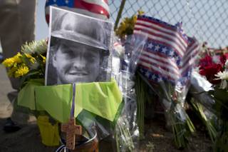 A photo of one of the 19 Granite Mountain Hot Shot crew members who was killed fighting a wild land fire near Yarnell, Ariz. on Sunday, sits at a makeshift memorial outside the crew's fire station, Monday, July 1, 2013 in Prescott, Ariz. An out-of-control blaze overtook the elite group of firefighters trained to battle the fiercest wildfires, killing 19 members as they tried to protect themselves from the flames under fire-resistant shields. 