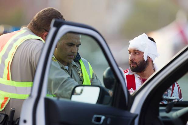 Metro Police officers talk to an injured fan after a fight between fans of Chivas Guadalajara and Club America before El Super Clasico soccer game at Sam Boyd Stadium, Wednesday, July 3, 2013. Witnesses said 150-200 people were involved in the altercation.