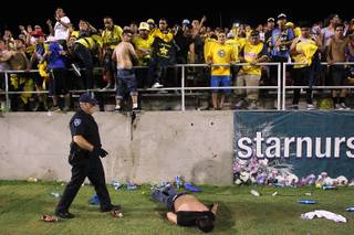A Chivas fan lies motionless on the field after being beaten nearly unconscious by Club America fans after El Super Clasico soccer game Wednesday, July 3, 2013 at Sam Boyd Stadium.