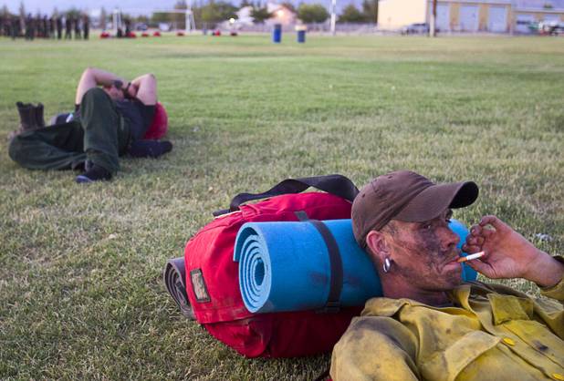 Firefighter Troy Thomas, based in Owyee, Nev. smokes a cigarette before making camp in Pahrump after fighting the Carpenter 1 wildfire Sunday, July 7, 2013.