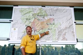 Rod Collins, an operation section chief for the National Incident Management Team briefs the night shift firefighters before they head out to the Carpenter 1 wildfire from Centennial High School on Monday, July 8, 2013.