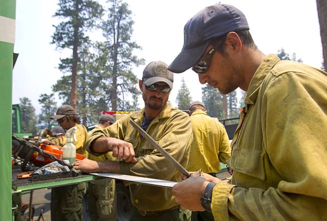 Evan, O'Shea, center, and Sean Alvarez, right, members of the Stanislaus Hot Shots based in Sonora, Calif., work on a chainsaw on Mount Charleston Tuesday, July 9, 2013.
