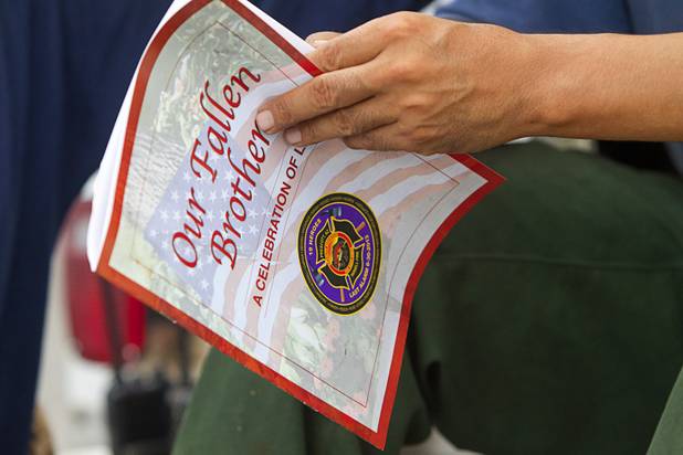 William "Alaska Hensley, based in San Carlos, Ariz., reads a memorial program from a service for 19 fallen firefighters as firefighters prepare to leave Centennial High School and fight the Mount Charleston wildfire Thursday, July 11, 2013. The Hot Shot firefighters were killed June 30 fighting the Yarnell Hill Fire in Arizona.