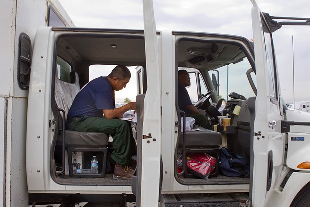 Jeremy Little, left, reads a memorial program from a service for 19 fallen firefighters as firefighters prepare to leave Centennial High School and fight the Mount Charleston wildfire Thursday, July 11, 2013. The Hot Shot firefighters were killed June 30 fighting the Yarnell Hill Fire in Arizona. Dwayne Bylas is at right. The firefighters are based in San Carlos, Ariz.