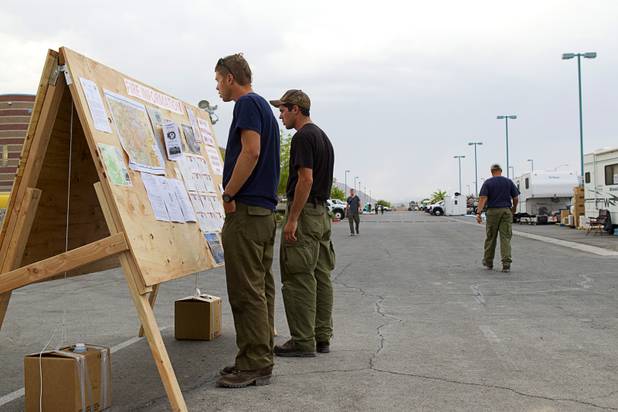 Firefighters read an information board at Centennial High School before leaving to fight the Mount Charleston wildfire Thursday, July 11, 2013.