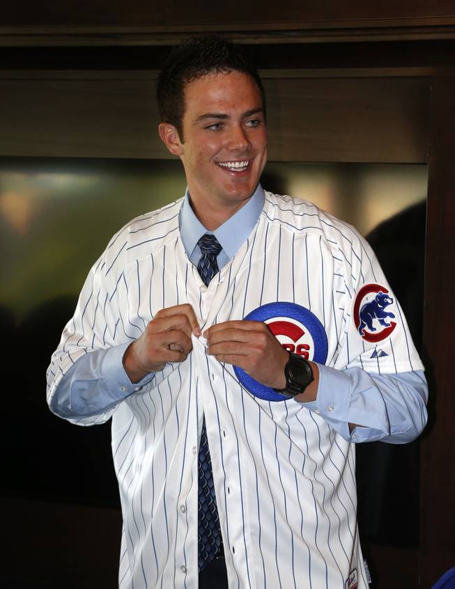 Chicago Cubs' first-round draft pick, third baseman Kris Bryant smiles as he puts on his jersey during a news conference where he was introduced to the media before a baseball game between the Chicago Cubs and the St. Louis Cardinals Friday, July 12 2013, in Chicago. 