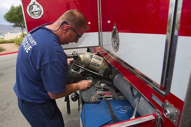 Firefighter/paramedic Mark Secrist stores self-contained breathing apparatus, used during structure fires, into a brush truck at Centennial High School Sunday, July 14, 2013.