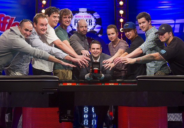The November Nine reach for the championship bracelet held by tournament director Jack Effel, center, during the World Series of Poker $10,000 buy-in no-limit Texas Hold 'Em at the Rio Tuesday morning, July 16, 2013. Players from left are: Sylvain Loosli, Michiel Brummelhuis, Mark Newhouse, Ryan Riess, Amir Lehavot, Marc McLaughlin, JC Tran, David Benefield and Jay Farber.