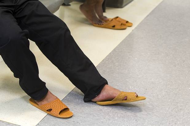 Men wear sandals in a booking area during a tour of the Clark County Detention Center Tuesday, July 23, 2013. Shoes are removed until their release.