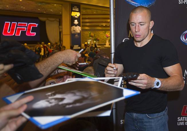 UFC welterweight champion Georges St. Pierre of Canada signs autographs for fans during a UFC news conference in the lobby of the MGM Grand on Monday, July 29, 2013. St. Pierre will defend his welterweight title against Johny Hendricks of Dallas, Texas, during UFC 167 on Nov. 17 at the MGM Grand.