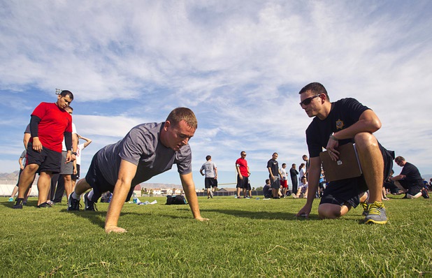 Metro Police recruit candidate Steven Kinsland, 25, performs 24 push-ups as Metro Corrections Officer Jon Clark looks on during physical fitness testing at Cimarron-Memorial High School Thursday, Aug. 1, 2013.