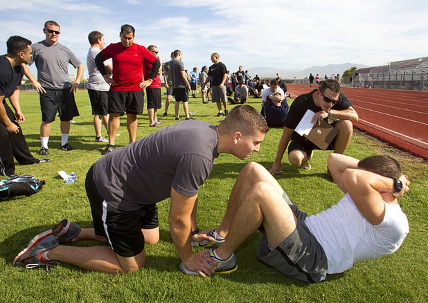 Metro Police recruit candidate Sean Pascoe, left, 21, holds the feet of his twin brother Chris during physical fitness testing at Cimarron-Memorial High School Thursday, Aug. 1, 2013. Candidates need to perform 32 sit-ups in one minute.
