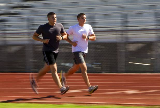 Metro Police recruit candidates and twin brothers Sean, left, and Chris Pascoe show identical form as they run for one mile during  physical fitness testing at Cimarron-Memorial High School Thursday, Aug. 1, 2013. The mile run must be completed in 10 minutes and 49 seconds or less.