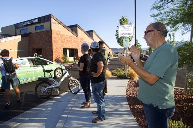 Las Vegan Don Carrier, right, owner of a Tesla S electric car, applauds as members of the "Ride to the Future Tour" arrive at Las Vegas Cyclery near I-215 and Town Center Drive Sunday, Aug. 4 2013. The tour of electric vehicles hopes to be certified for several Guinness World Records. The cross-country tour began July 4th in Charleston, South Carolina, and will end at Google Headquarters in Mountain View, Calif. on August 16.