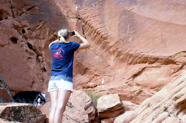 Chiara Velotta photographs petroglyphs on a rock outcropping at Gold Butte, Aug. 4, 2013.