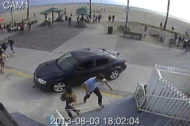 In this image take from a security camera, pedestrians scatter as a car drives through a packed afternoon crowd along the Venice Beach boardwalk in Los Angeles on Saturday, Aug. 3, 2013. 