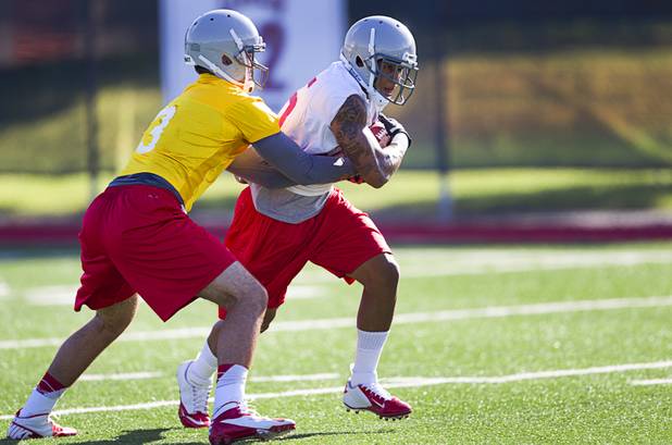 Running back Tim Cornett, right, takes a handoff from quarterback Nick Sherry during practice at UNLV Tuesday, Aug. 6, 2013.